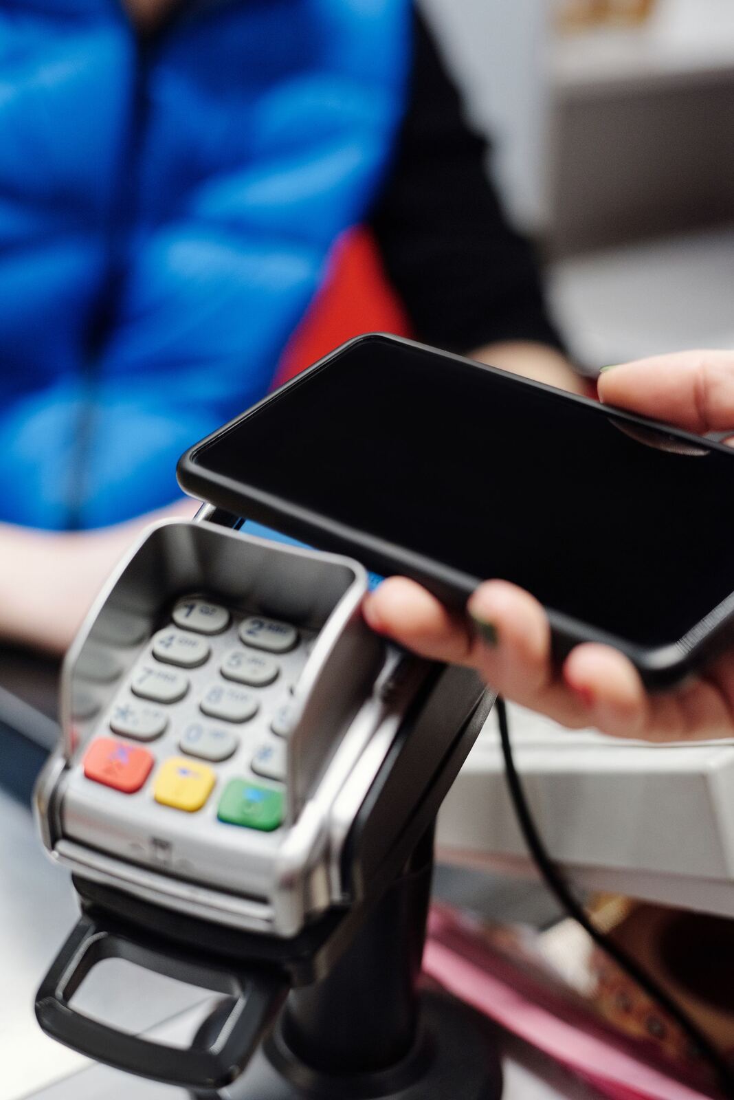 Mano acercando un teléfono a un datáfono para pagar sin contacto